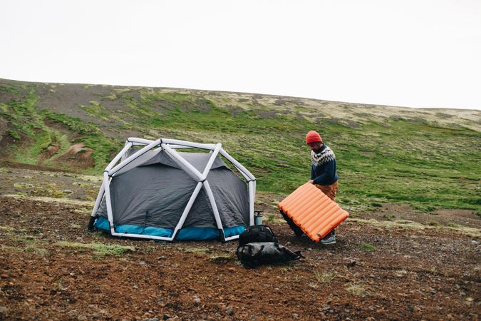 Man setting up bed in camp in field