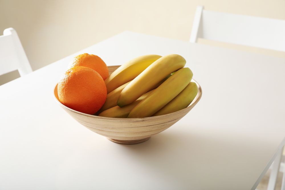 Bowl with oranges and bananas on table
