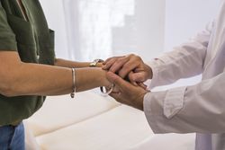 Male doctor holding hands with his female patient at the hospital.