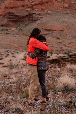 Two people hugging on soil field