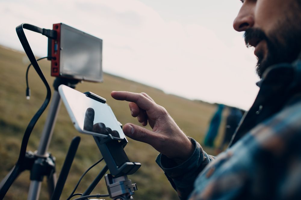 Side view of man using two smartphones attached to screen stand outdoor