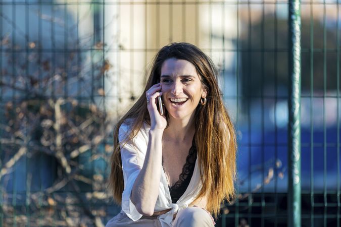 Laughing woman wearing casual clothes talking on phone