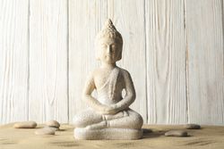 Buddha on sand against wooden background. Zen concept
