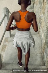 Rear view of a fitness woman running down the steps outdoors 5QP3g0
