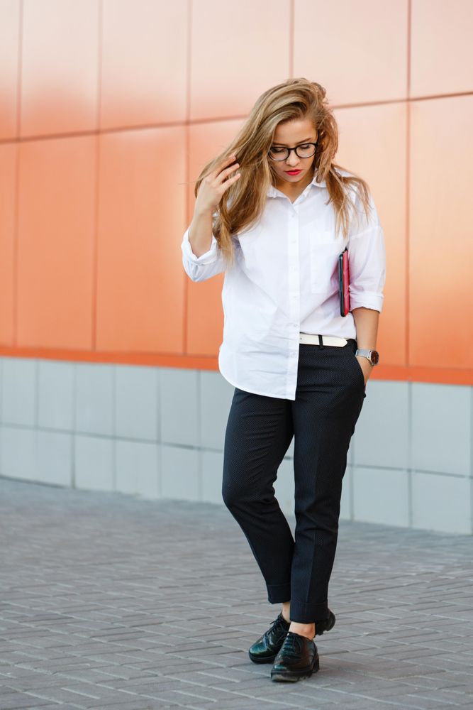 Woman in glasses in front of orange wall, vertical
