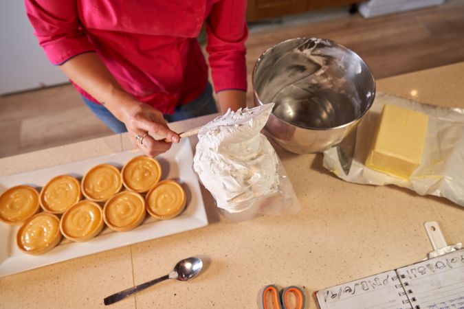 Faceless female chef filling pastry bag with butter cream