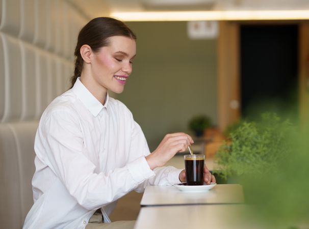 Elegant woman drinking coffee in a modern cafeteria