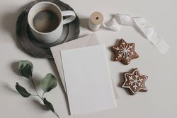 Christmas still life with blank card next to gingerbread cookies and warm drink