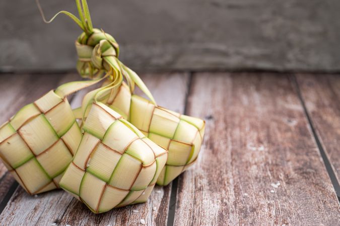 Uncooked ketupat filled with rice, placed on wooden surface