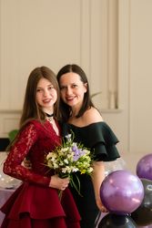 Teen girl holding bouquet flowers standing with woman.