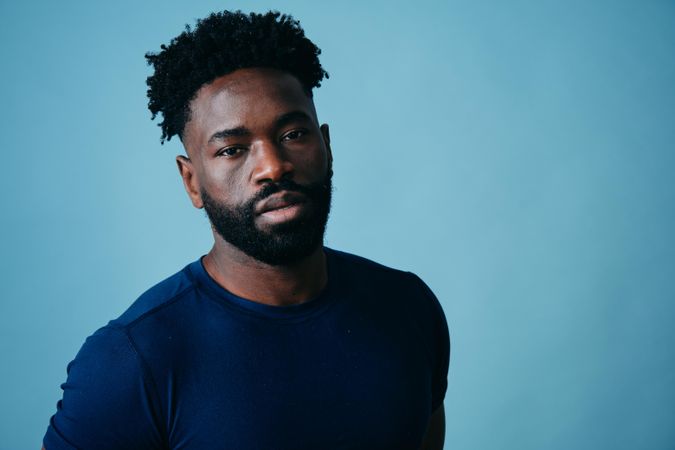 Black male model posing in blue studio with serious expression