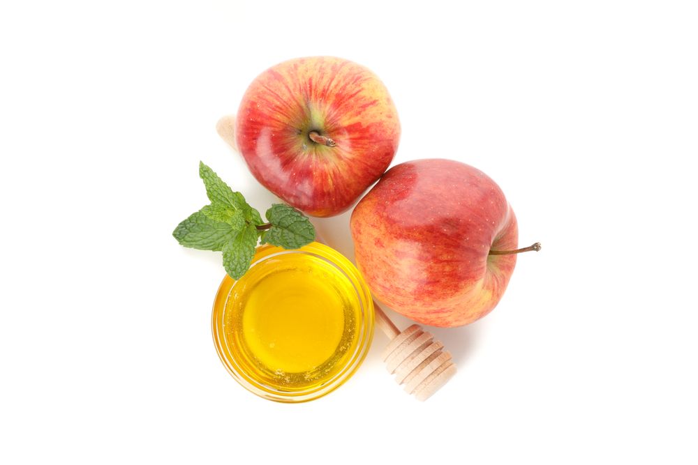 Top view of two apples, leaves and a pot of honey