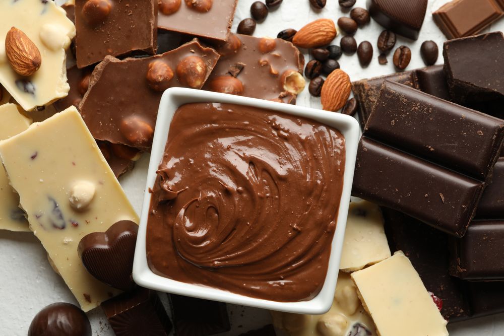 Chocolate, melted chocolate, coffee and almond on blank background