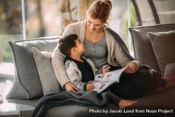 Happy mother and son sitting on couch with a story book living room 4BmrB5
