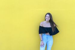 Happy woman leaning on yellow wall on a sunny day
