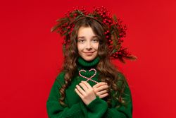 Girl in green sweater holding two candy canes