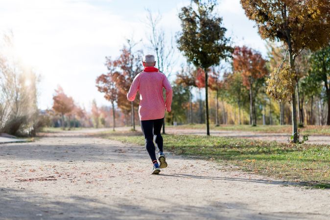 Back of mature man jogging outside in park