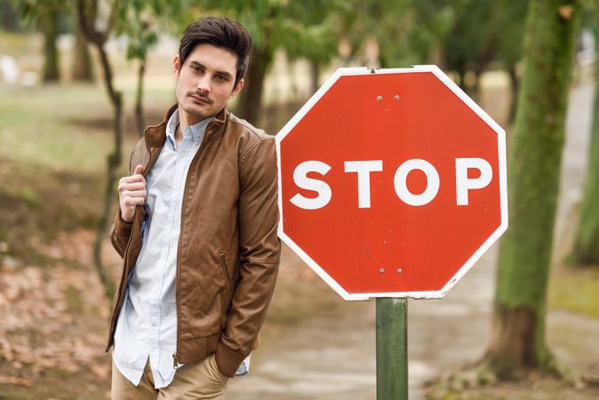 Man leaning against stop sign in park