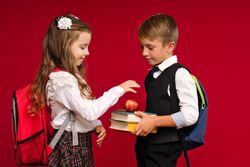 Preteens in school uniform carry backpacks on vivid red colored background