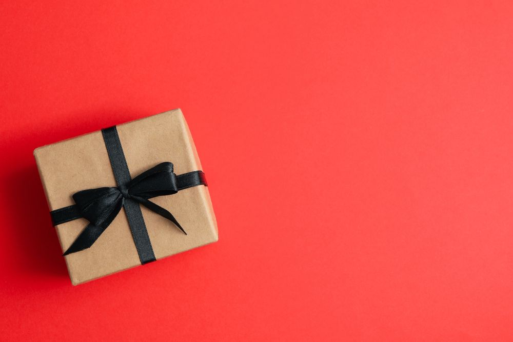 Gift box with dark bow on red background