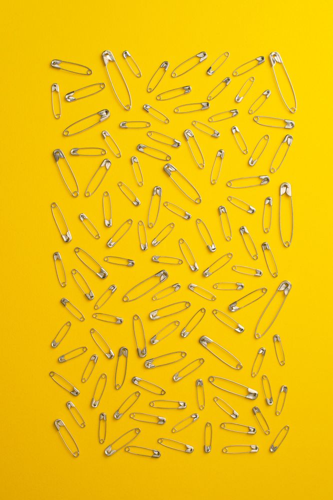 Scattered safety pins on yellow background