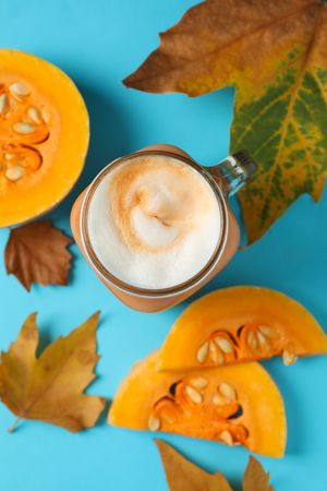 Composition with glass jar of pumpkin latte on blue background