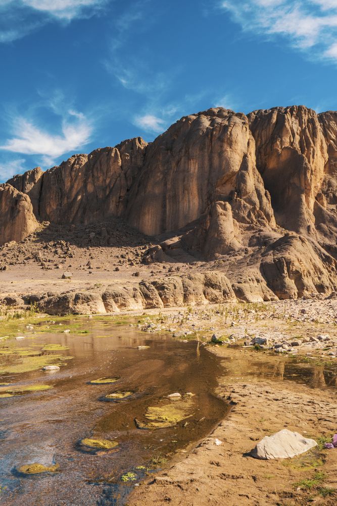 Narrow river near stone hill in desert