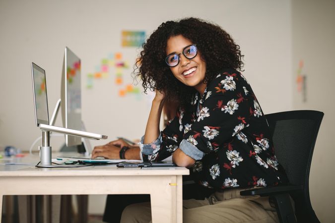 Young woman wearing eyeglasses working on laptop sitting in office