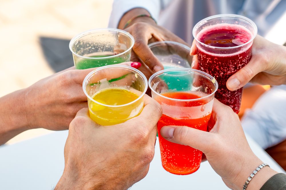 Close-up of friends toasting with colorful drinks outdoors