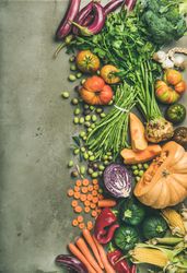 Fresh produce on concrete, with halved squash, corn, cabbage, vertical composition, copy space