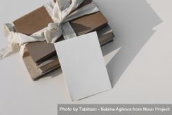 Blank greeting card on top of stack of books tied up with beige ribbon 5wzx90