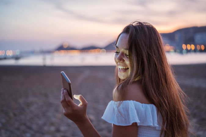 Cheerful young woman using smartphone on resort