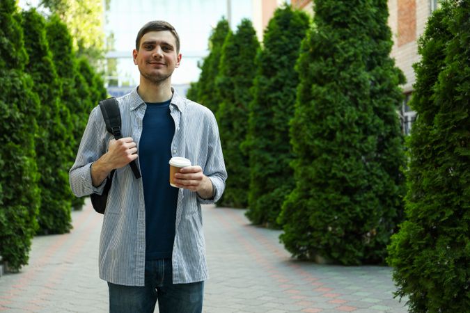Young student hold backpack and cup of coffee. Study. University
