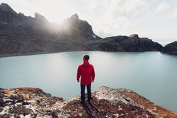 Back view of man standing on waterside of frozen lake during daytime