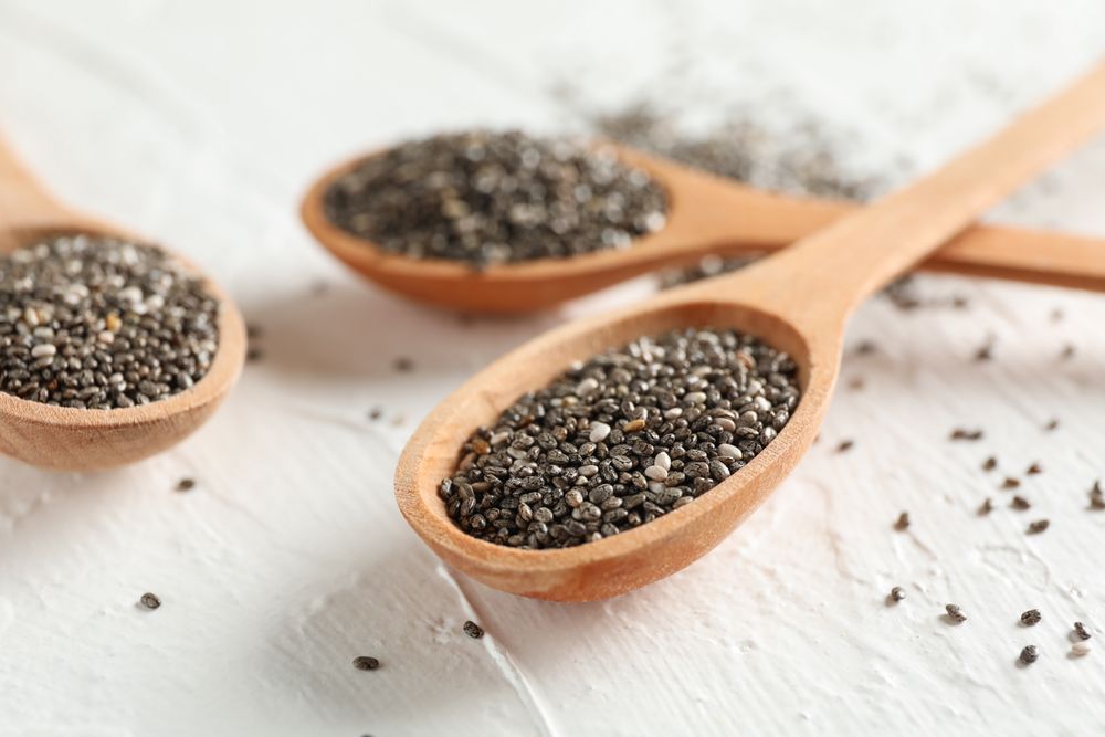 Wooden spoons and chia on neutral background, close up