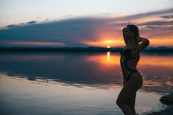 Sensual woman against sunset sky on beach