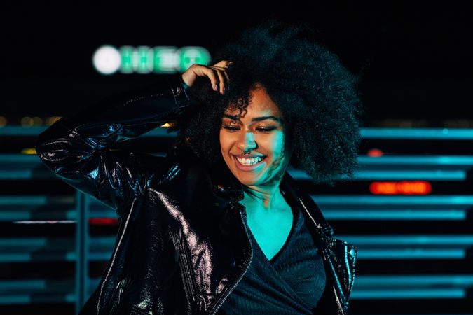 Happy Black woman on a rooftop in blue green light