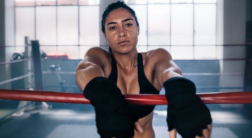 Confident female boxer inside a boxing ring with hands wrapped