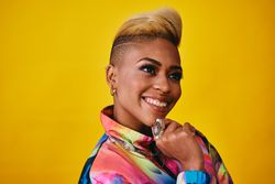 Studio shot of confident Black woman in bright 80s windbreaker jacket looking away with hand on chin