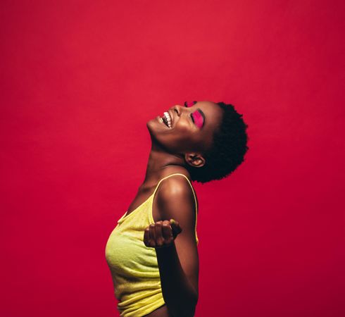 Cheerful young woman dancing over red background