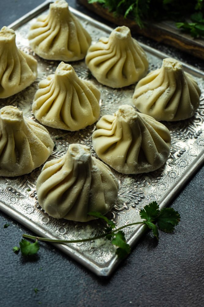Trey of raw Georgian khinkali dumplings with cilantro