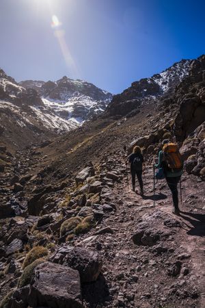 Tourists walking up mountain slope at sunny day