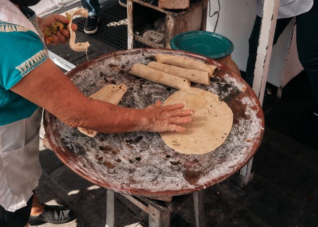 Woman moving tortillas on ceramic griddle