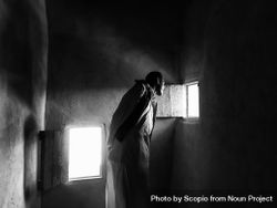 Grayscale photo of man in a small room looking through the small shutter in Siwa oasis, Egypt 41vAOb