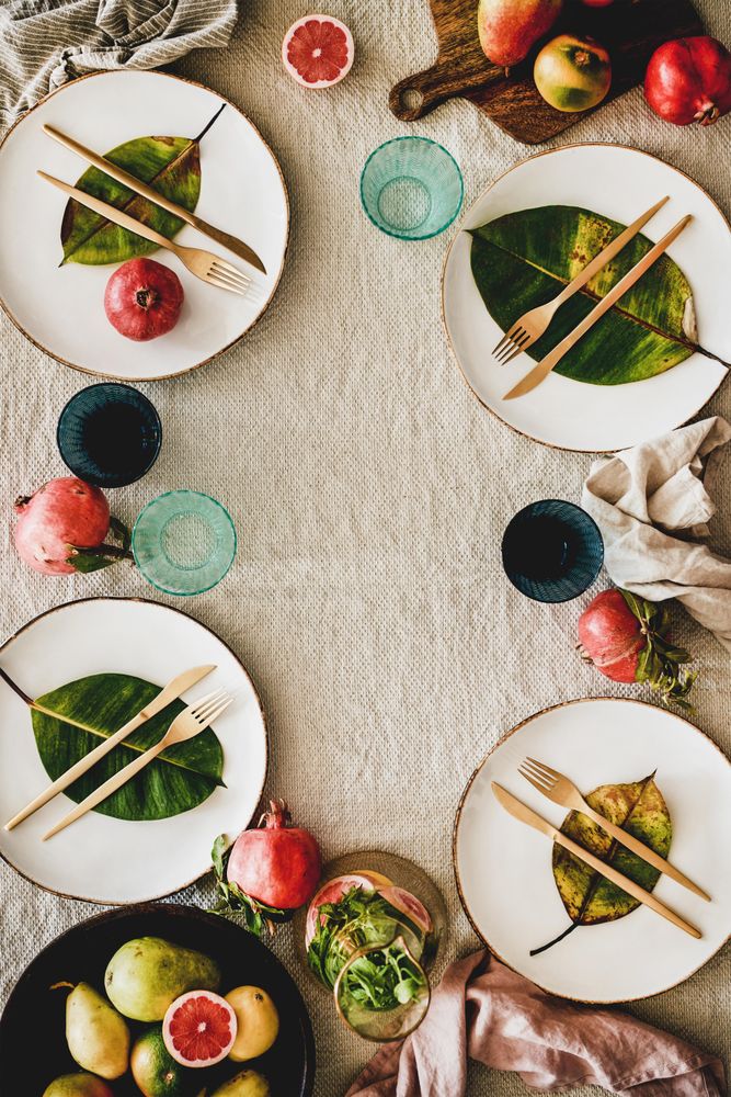 Fresh table setting on brown table cloth, leaves on bright plates, fruit, vertical, copy space