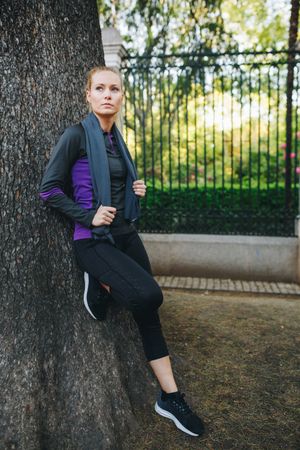 Woman resting on tree trunk after jogging