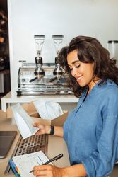 Woman checking calendar in coffee shop while holding bag of beans