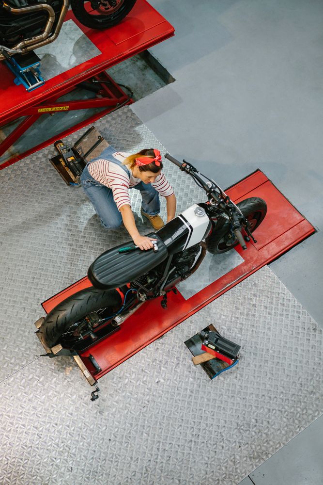 Mechanic woman reviewing custom motorcycle over platform