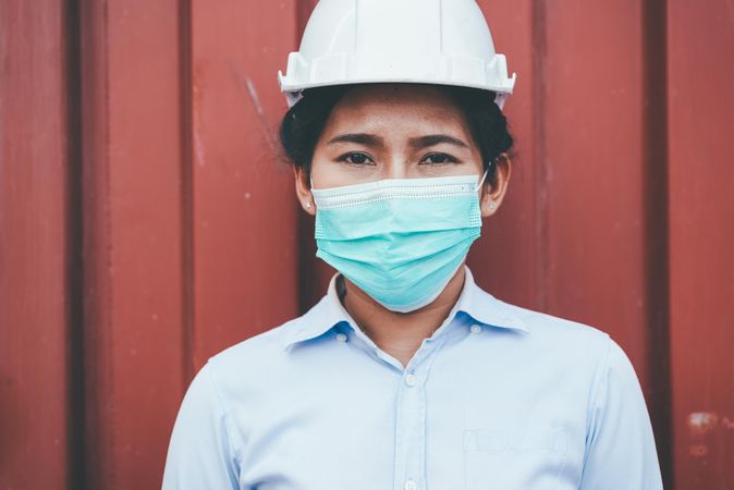 Portrait of logistic engineer woman wearing protective mask looking at camera