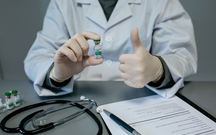 Doctor with thumb up while showing coronavirus vaccine